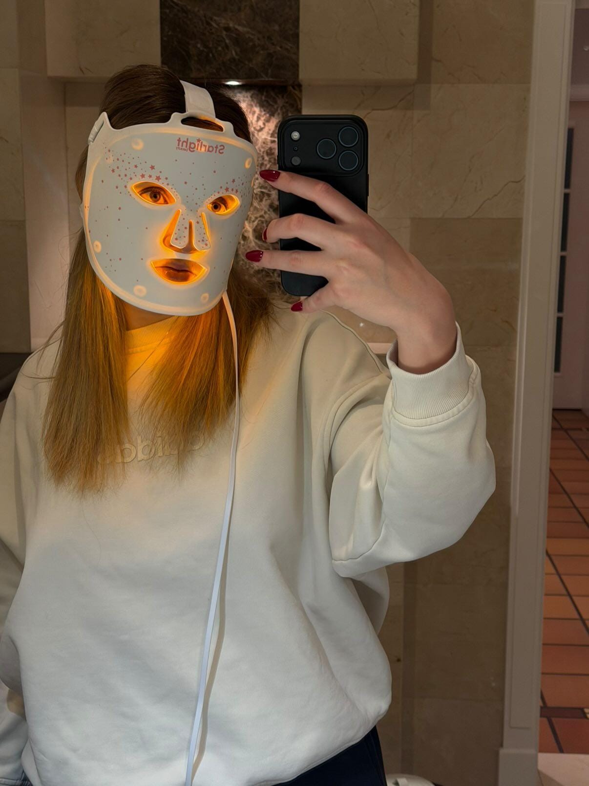 Woman wearing the Starlight LED therapy mask glowing warm red